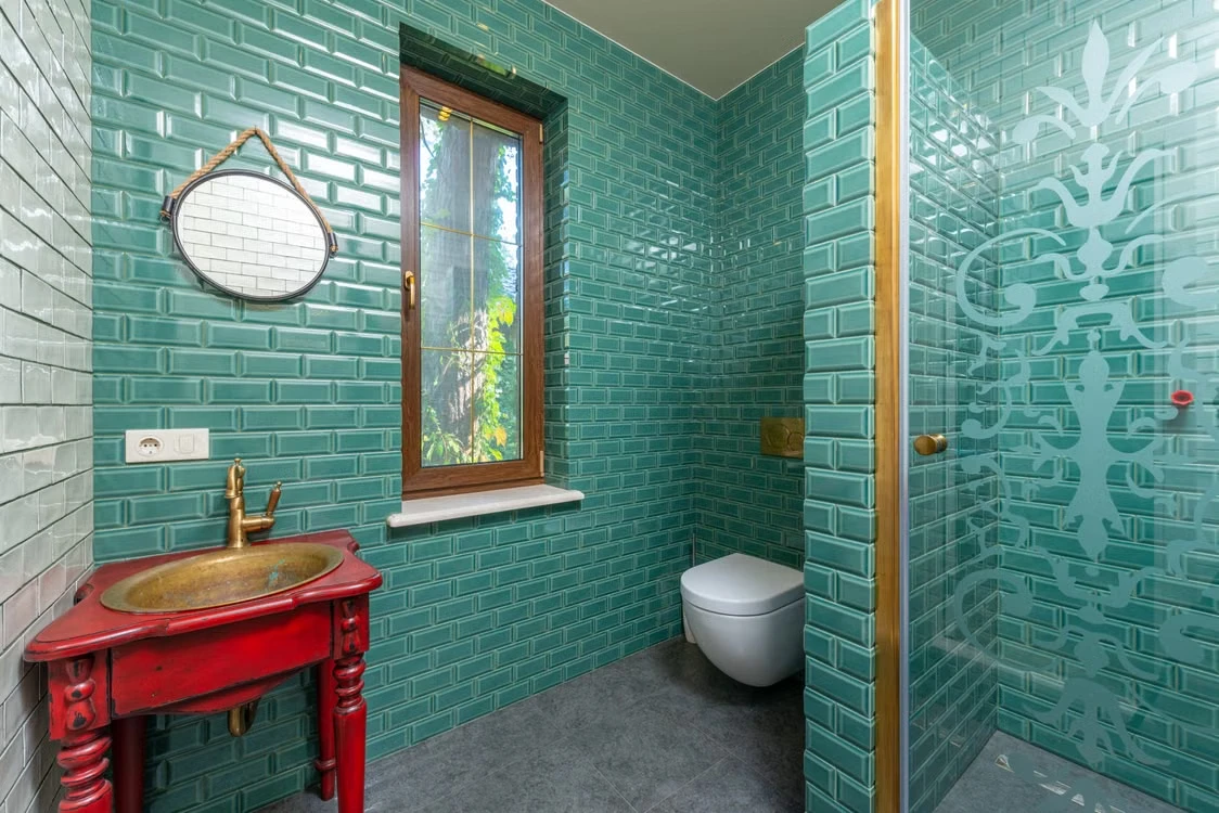 Inspiratiebeeld van een badkamer met kleurrijke turquoise wandtegels en gouden accenten